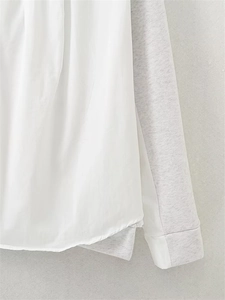 Detail showing contrast fabric patchwork and ribbed cuff on a loose white and grey hoodie