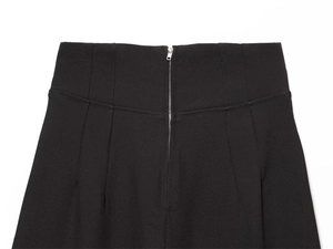 Dettaglio della cerniera posteriore e della vita alta a pieghe sui pantaloni neri eleganti