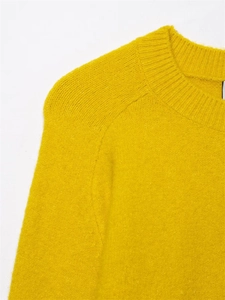 Detail of soft yellow knit sweater showing classic crewneck and fuzzy mohair texture