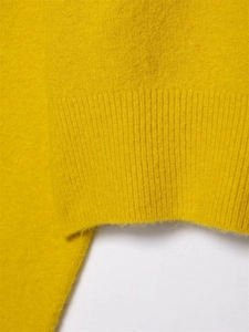 Macro shot of bright yellow knitted sweater showing soft brushed texture and ribbed cuffs