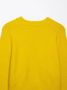 Detail of soft mustard yellow knit sweater showing ribbed crew neck and plush texture