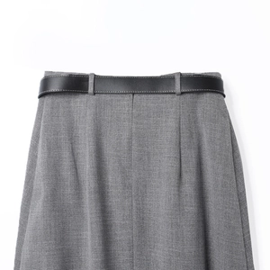 Detalle de la cintura de falda midi plisada gris con cinturón de cuero negro pespunteado