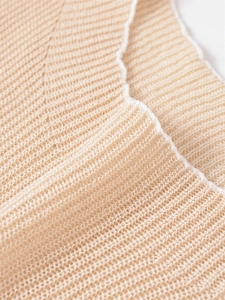 Macro detail of apricot ribbed knit fabric with contrast white piping and fine texture