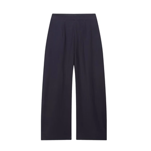 Detail van de donkerblauwe pantalon met wijde pijpen, hoge taille, plooien en soepele val