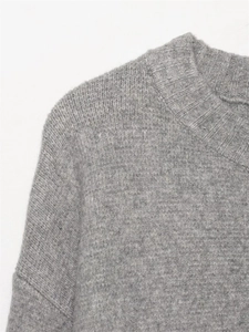 Primer plano de suéter de punto gris con cuello redondo acanalado y textura de tela suave