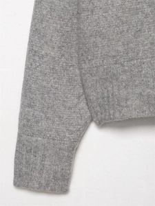 Detalle de jersey de punto gris claro con puños acanalados y textura de lana suave