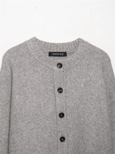 Detalle de cárdigan de punto gris suave con botones de resina y etiqueta tejida de marca