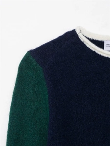 Détail du pull en maille bleu marine et vert avec une texture en mohair duveteux