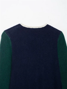 Détail d'un pull en maille contrasté avec corps bleu marine et manches vertes au col crème