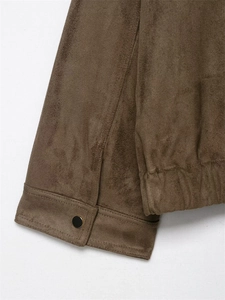Detail einer braunen Wildlederjacke mit schwarzem Knopf und elastischem Saum-Design