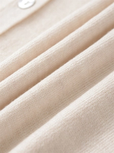 Detailansicht der weichen beigen Strickstruktur mit einem weißen Knopf-Akzent