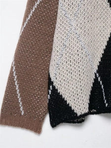 Detail eines weichen Strickpulloverärmels mit Argyle-Muster in Braun, Creme und Schwarz