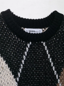 Nahaufnahme des Rundhalsausschnitts eines dreifarbigen Strickpullovers mit Rautenmuster