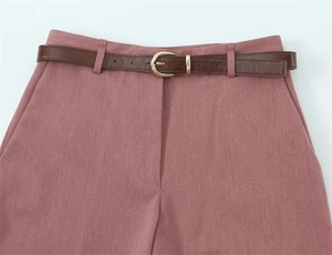 Dettaglio dei pantaloni a vita alta con cintura marrone effetto coccodrillo e fibbia oro