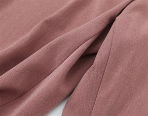 Dettaglio del tessuto twill rosa che mostra la trama fine e il drappeggio morbido