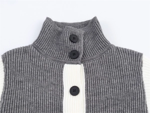 Dettaglio di tre bottoni neri su un cardigan in maglia bicolore a collo alto grigio
