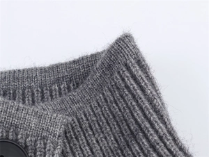 Vista dettagliata del tessuto a maglia grigio con collo a coste e bottone nero