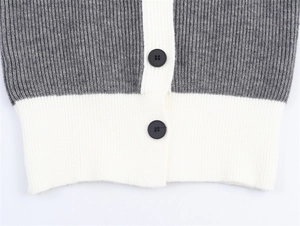 Vista macro del cardigan in maglia bicolore grigio e bianco con trama a coste e bottoni neri