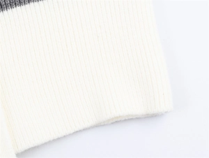 Vista macro della trama in maglia a coste crema e dettaglio righe grigio scuro sull'orlo