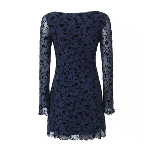 Detail of sheer mesh dress featuring black flocked floral patterns and wavy ruffle edges