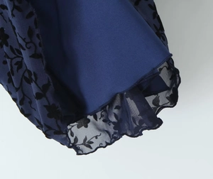 Detail of navy blue dress hem with black flocked floral mesh and ruffled wave edges