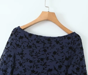 Detail of sheer mesh long sleeve dress with dark floral flocking texture on fabric