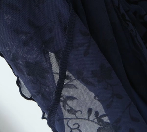 Detail of dark blue mesh dress with black flocked floral pattern and neat edge stitching