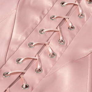 Detail showing the pink satin fabric with lace-up corset design and silver eyelets