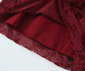 Detail of burgundy floral lace mesh fabric with tiered layers and wavy hem on a dress