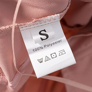 Detail of care label on pink corset top showing 100% polyester material and size S