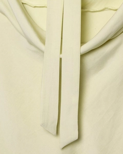 Detalle de la suave tela amarillo claro y costuras de precisión en las tiras del cuello