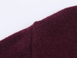 Dettaglio macro del tessuto a maglia bordeaux con cuciture fini e texture in lana