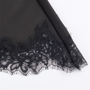 Detail van elegant zwart wimperkant en geplooide stof op een chique slipjurk voor dames
