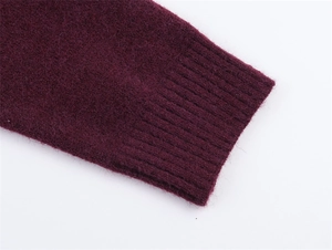 Dettaglio dei polsini a coste di un maglione in maglia bordeaux dalla trama soffice