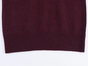 Dettaglio di un maglione bordeaux a maglia con bordo a costine e trama fine