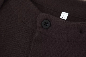 Detailed close-up of dark brown knit fabric with black buttons and a size L tag