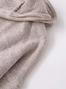 Detailed close-up of beige chunky knit texture and silver metal zipper on hooded cardigan