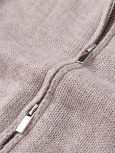 Macro shot of silver dual metal zippers on a beige knitted cardigan jacket for women