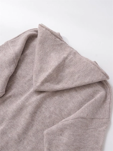 Close-up of light brown knitted hoodie with zipper closure and smooth fabric detail