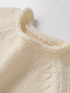 Gros plan du col rond côtelé sur un pull en maille douce de couleur crème pour femme