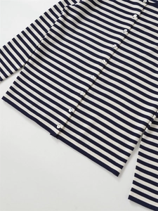 Detailed shot of white pearlescent buttons and striped pattern on navy knit cardigan