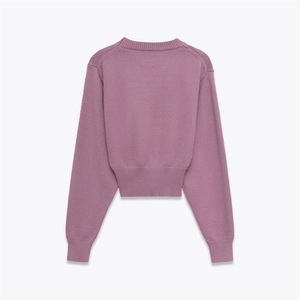 Detail view of purple knit sweater showing ribbed cuffs, round neck, and soft texture