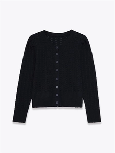 Détails du gilet noir en maille ajourée avec motifs ondulés et boutons ronds sur fond blanc