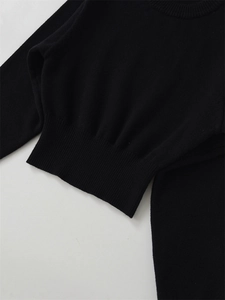 Detailed close-up of a black crew neck sweater showing ribbed hem and collar textures