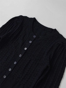 Détail d'un cardigan noir en tricot ajouré avec des boutons ronds assortis