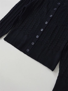 Détail d'un cardigan en maille bleu marine avec motifs crochet ajourés et bord côtelé