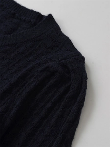 Détail du pull en maille torsadée bleu marine avec col rond et texture de laine douce
