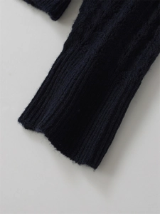 Détail d'un pull en maille torsadée bleu marine avec poignets côtelés et texture laine