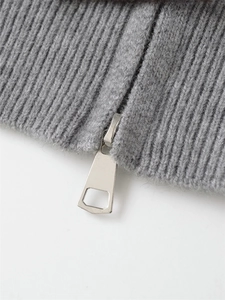 Close-up of the silver metal zipper and ribbed knit texture on a grey hooded jacket