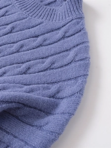 Dettaglio del maglione a trecce blu-viola che mostra la trama e il girocollo a coste